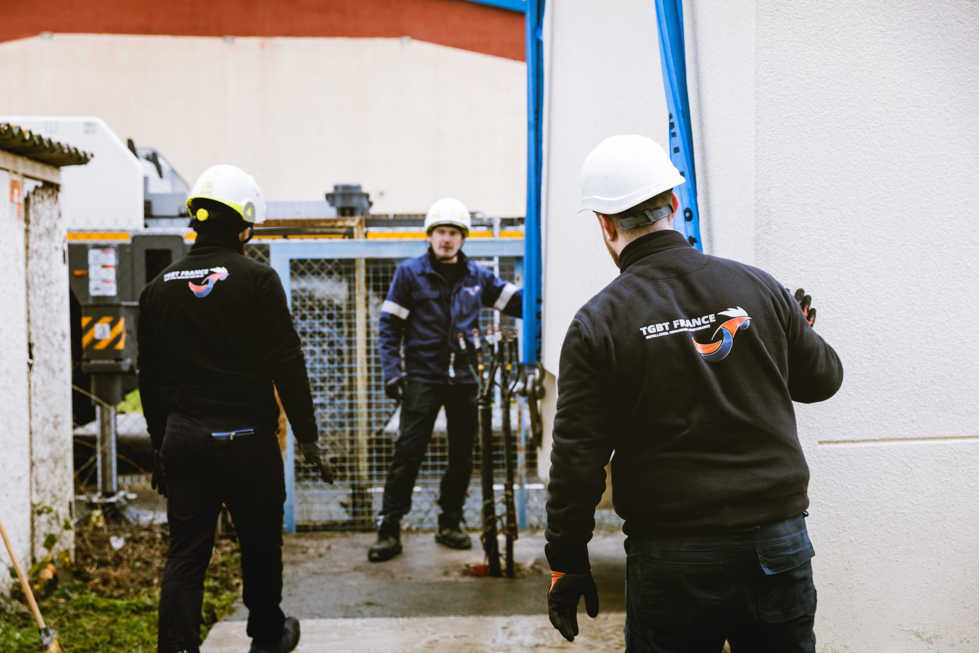Techniciens casqués lors du tirage de câbles haute tension sur un chantier, devant un poste électrique